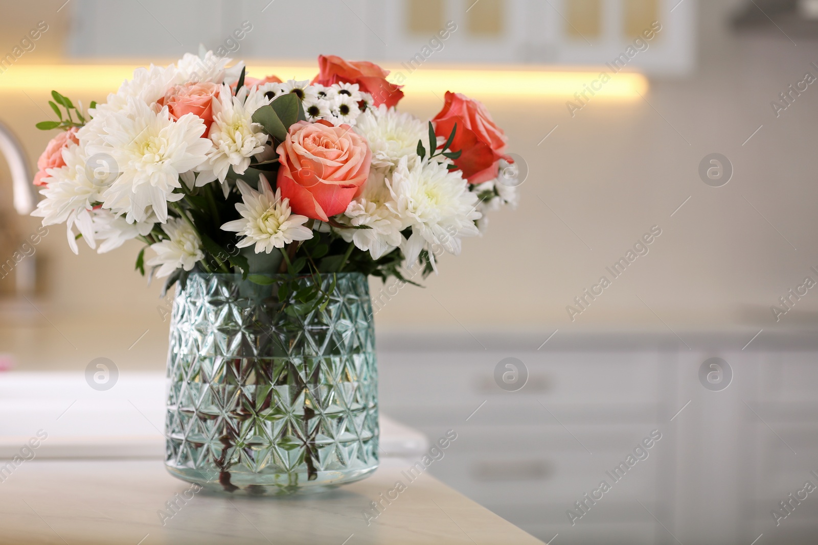 Photo of Vase with beautiful flowers on countertop in kitchen, space for text. Interior design