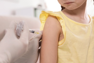 Family doctor vaccinating little child at home, closeup