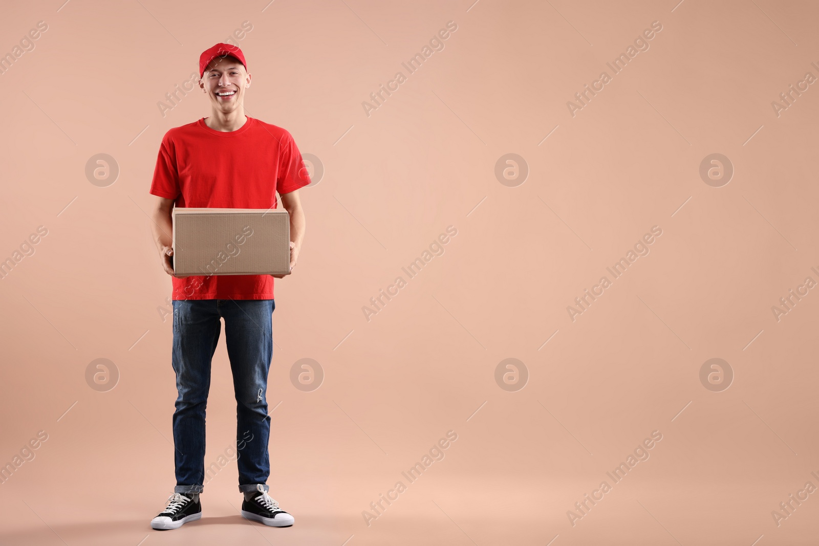 Photo of Happy courier with parcel on beige background. Space for text