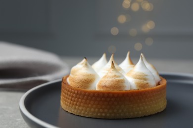Photo of Tartlet with meringue on grey table against blurred festive lights, closeup and space for text. Delicious dessert