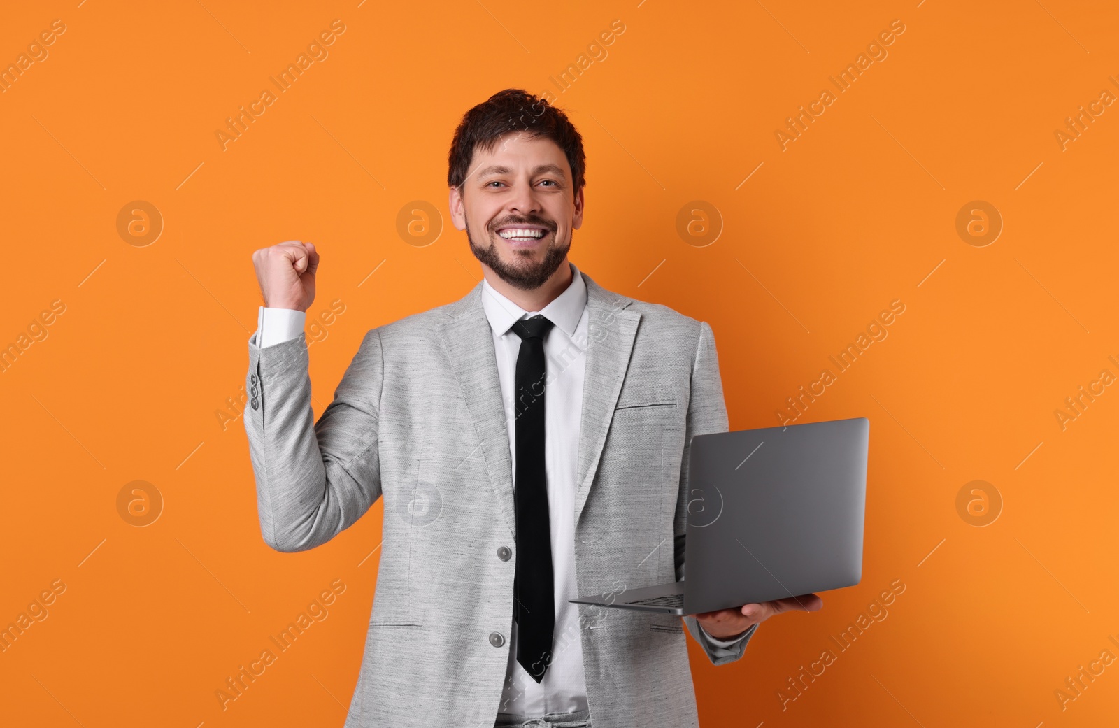 Photo of Happy man with laptop on orange background