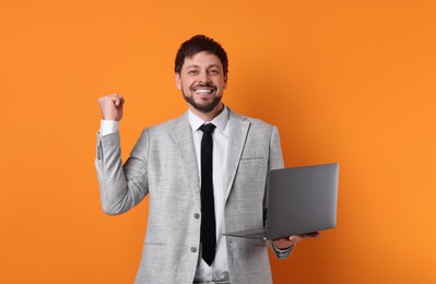 Happy man with laptop on orange background