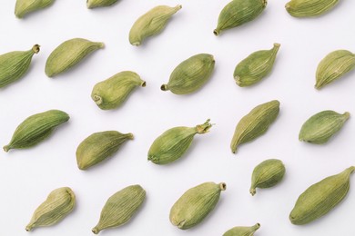 Many dry cardamom pods on white background, flat lay