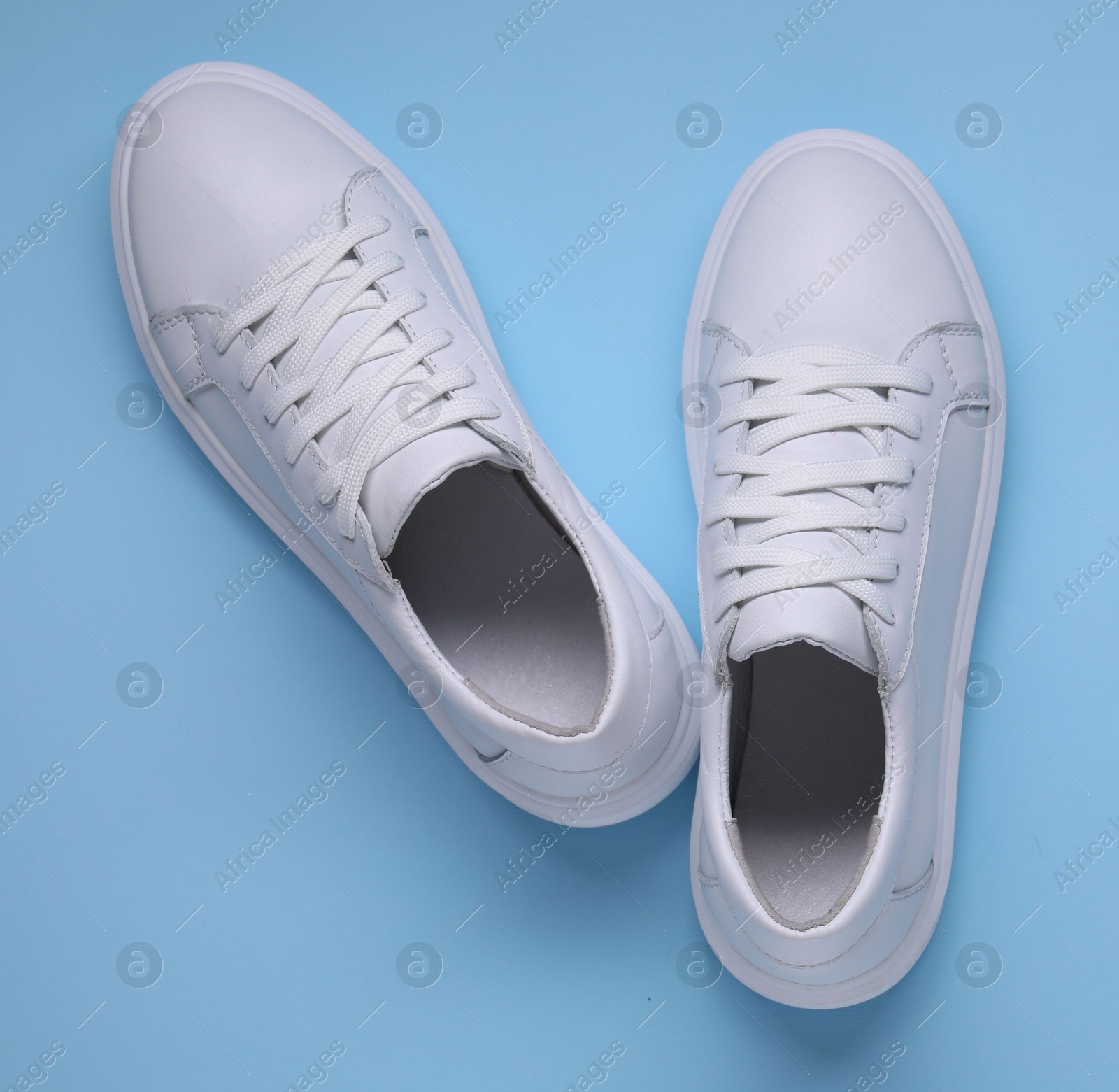 Photo of Pair of stylish white sneakers on light blue background, top view