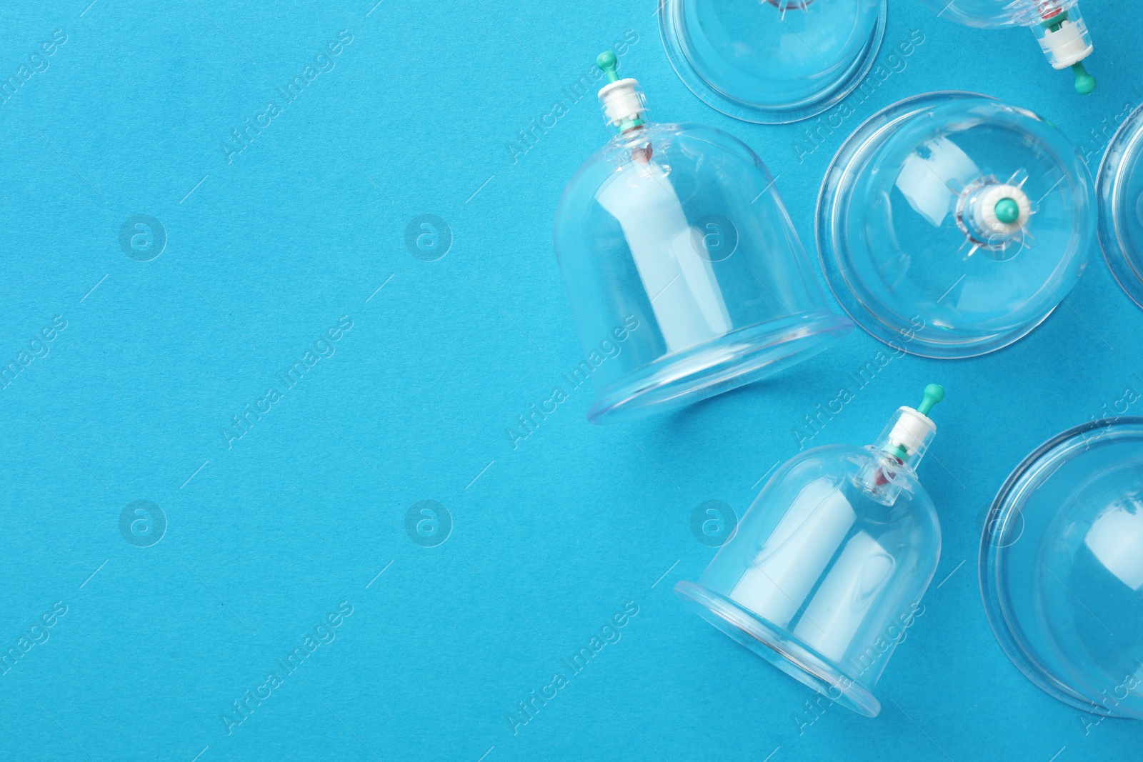 Photo of Plastic cups on light blue background, flat lay with space for text. Cupping therapy