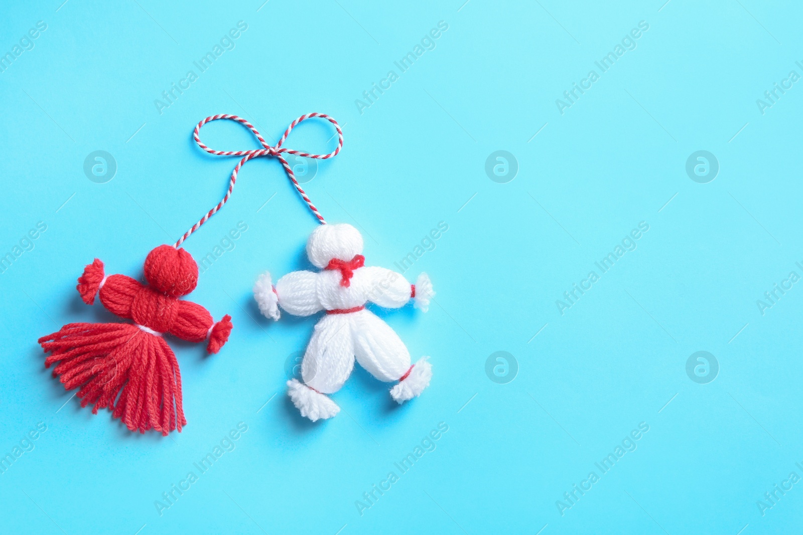 Photo of Traditional martisor shaped as man and woman on light blue background, top view with space for text. Beginning of spring celebration