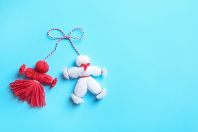 Photo of Traditional martisor shaped as man and woman on light blue background, top view with space for text. Beginning of spring celebration