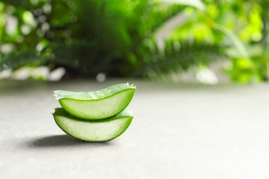 Fresh sliced aloe vera leaves on light table against blurred background with space for text