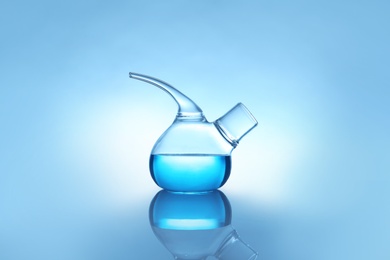 Photo of Retort flask with liquid on table against color background. Laboratory analysis