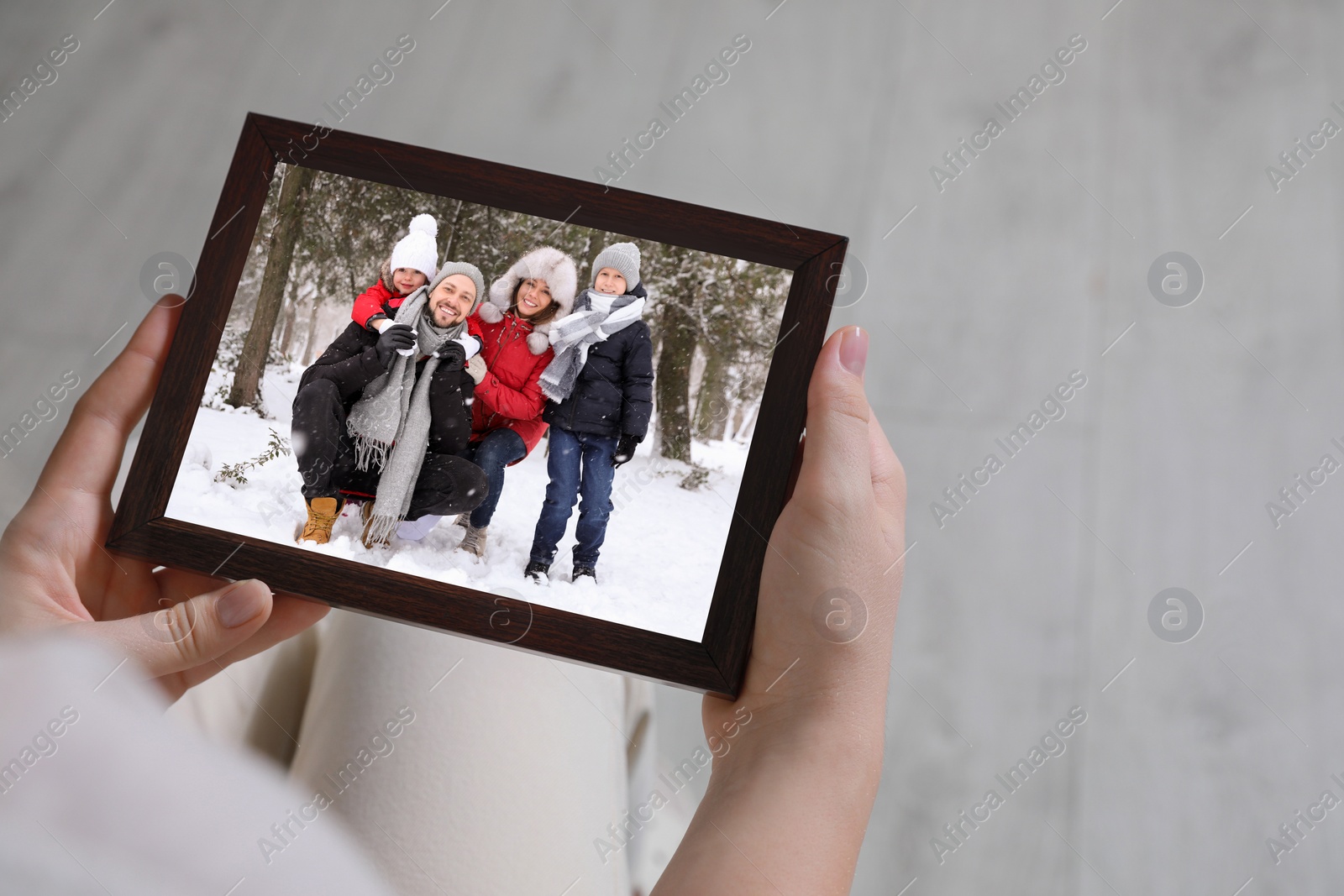 Image of Woman holding frame with photo portrait of her family indoors, closeup