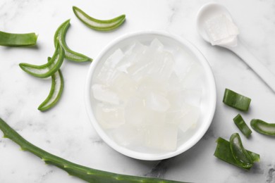 Aloe vera gel and slices of plant on white marble table, flat lay