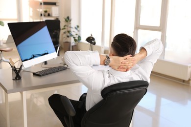Businessman relaxing in office chair at workplace, back view