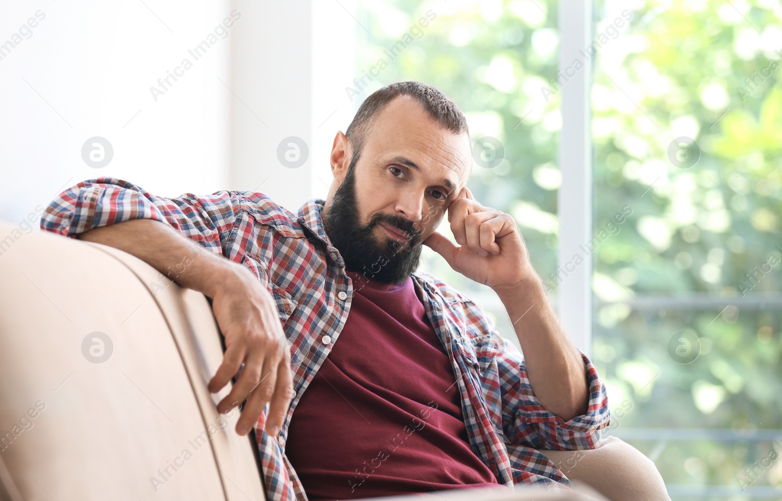 Photo of Portrait of handsome mature man sitting on sofa at home