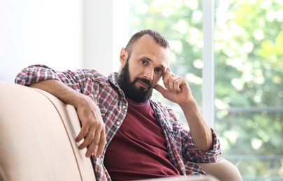 Photo of Portrait of handsome mature man sitting on sofa at home