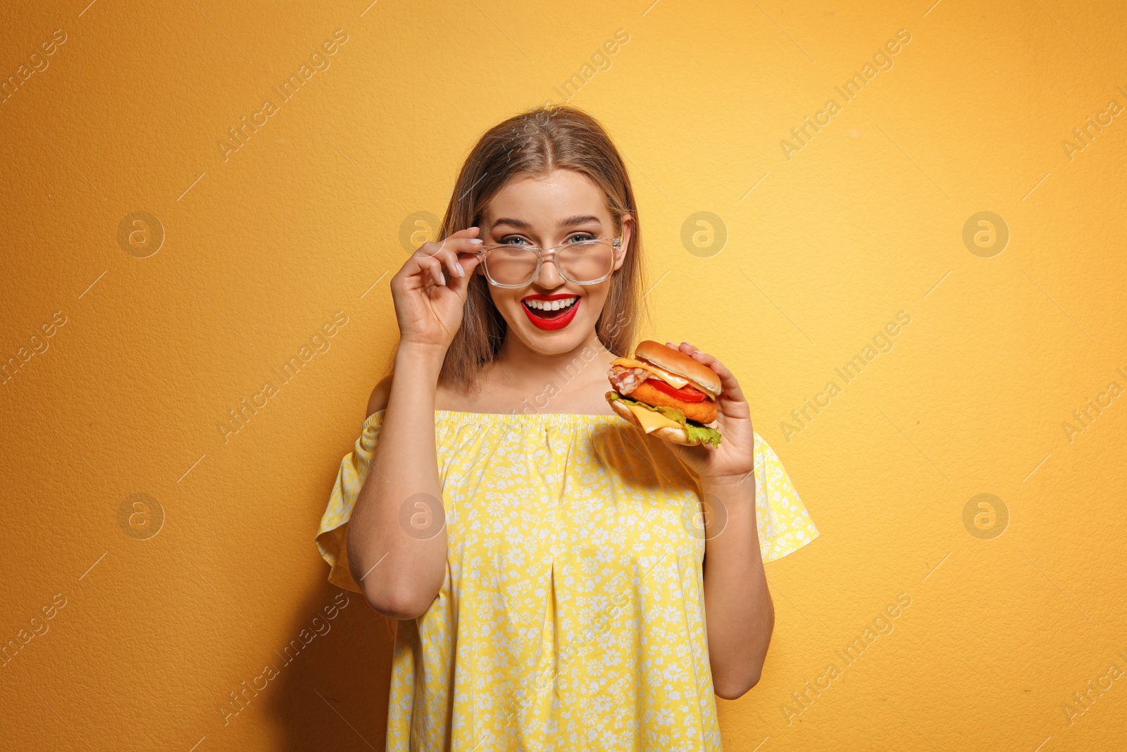 Photo of Pretty woman with tasty burger on color background