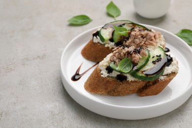 Delicious bruschettas with balsamic vinegar and toppings on light textured table, closeup. Space for text