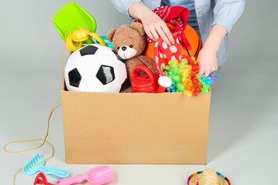 Photo of Woman with box of unwanted stuff on grey background, closeup