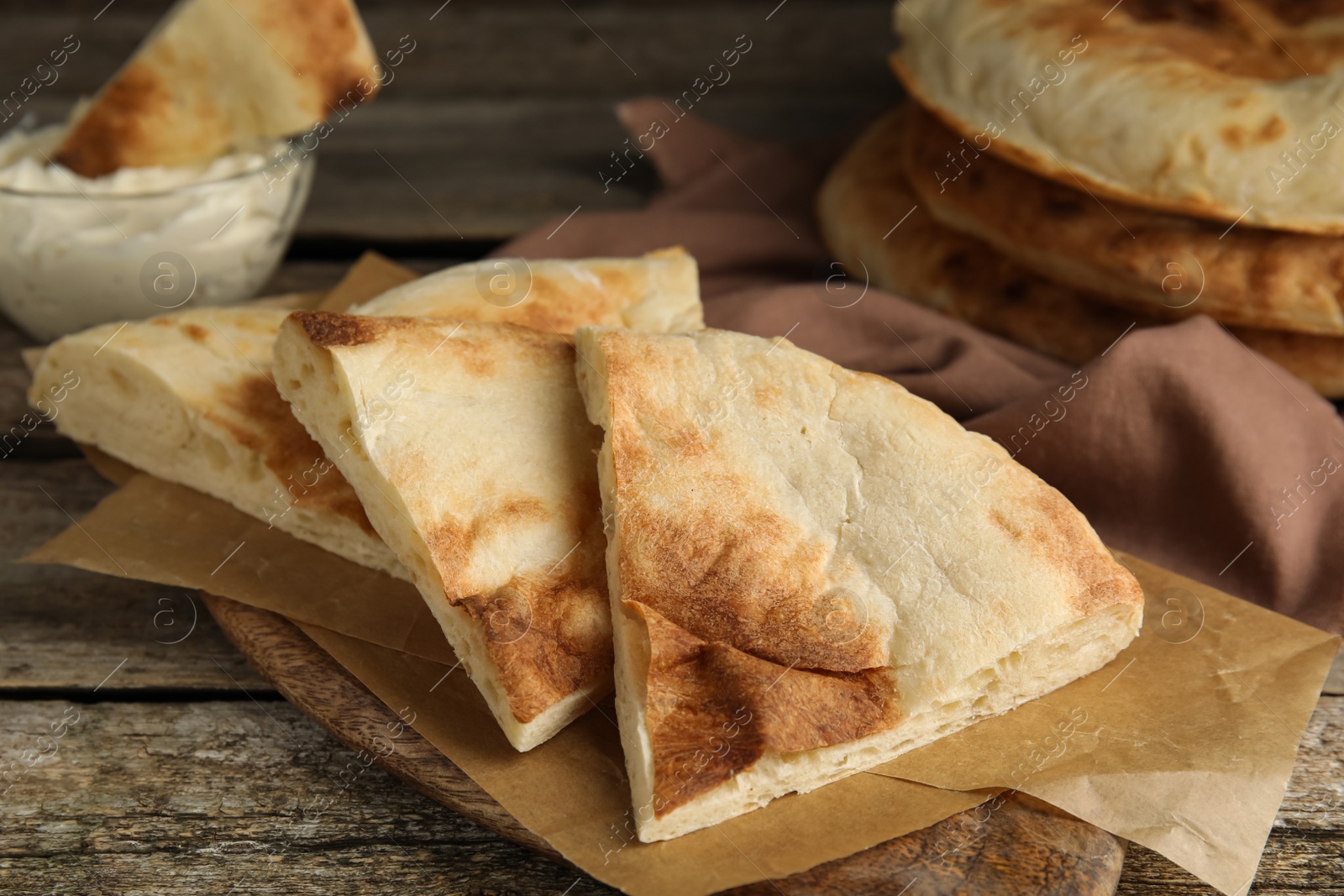 Photo of Pieces of fresh pita bread on wooden table, closeup