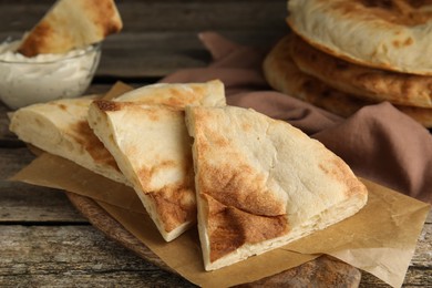 Pieces of fresh pita bread on wooden table, closeup