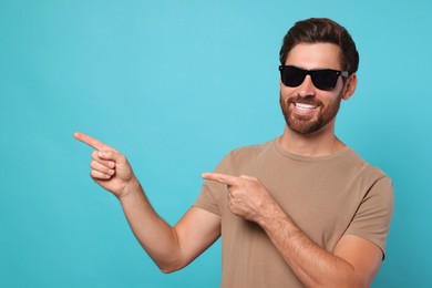 Portrait of smiling bearded man with stylish sunglasses on light blue background. Space for text