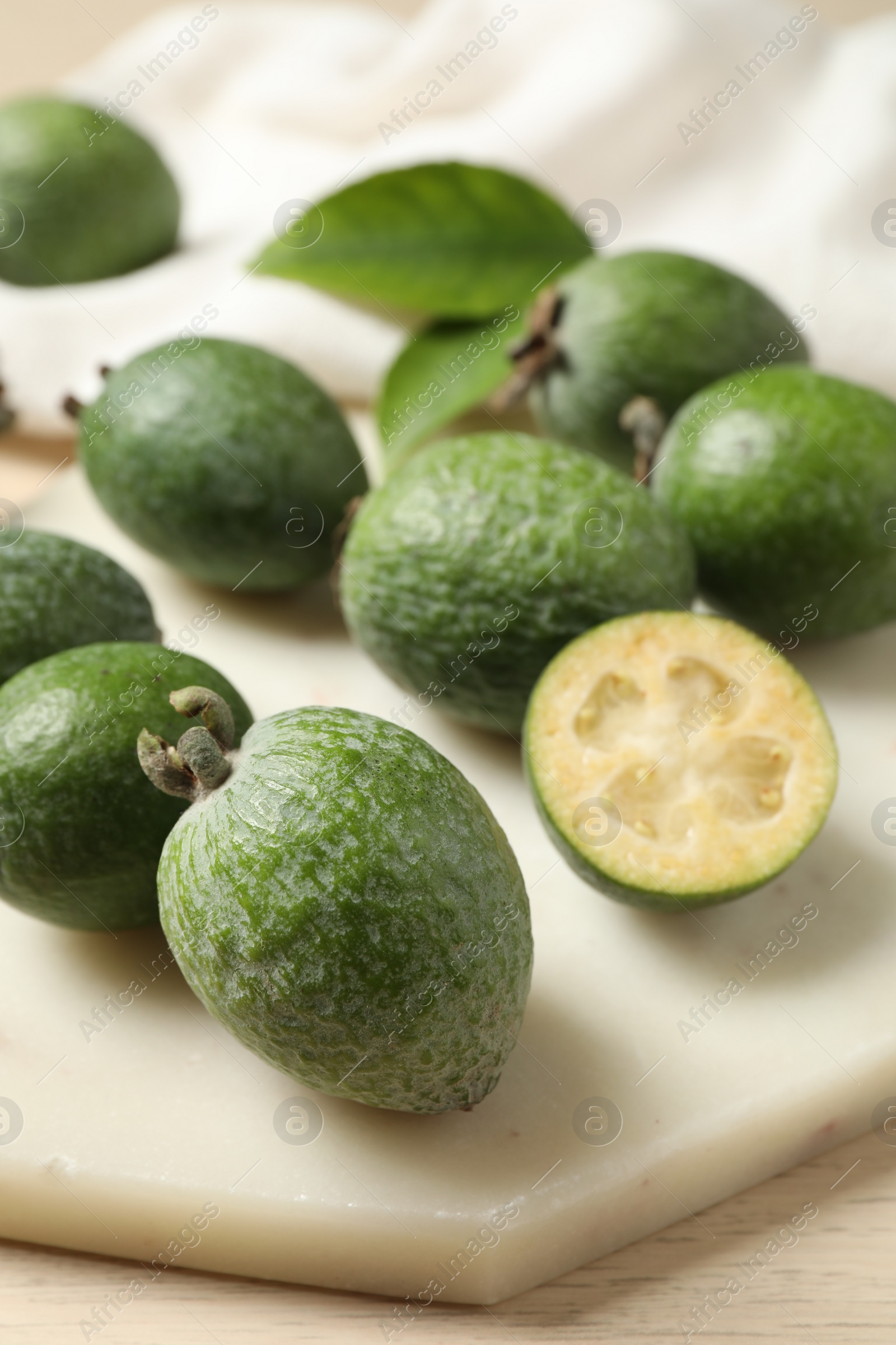 Photo of Fresh green feijoa fruits on white cutting board, closeup