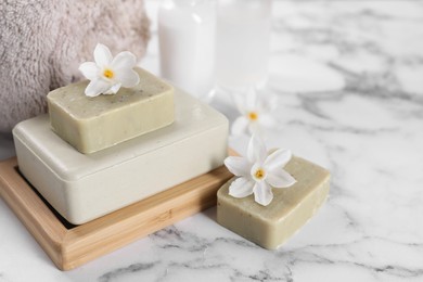 Photo of Spa composition with soap, flowers and towel on white marble table