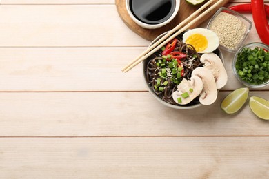 Photo of Tasty buckwheat noodles (soba) with egg and mushrooms served on wooden table, flat lay. Space for text