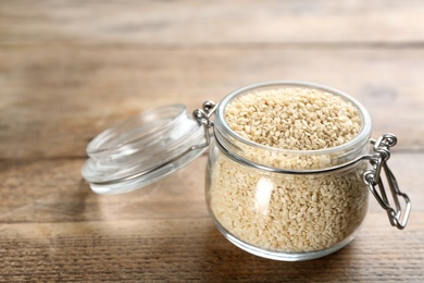 Photo of Sesame seeds in jar on wooden table
