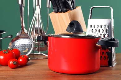 Photo of Set of clean cookware and utensils on table against color background