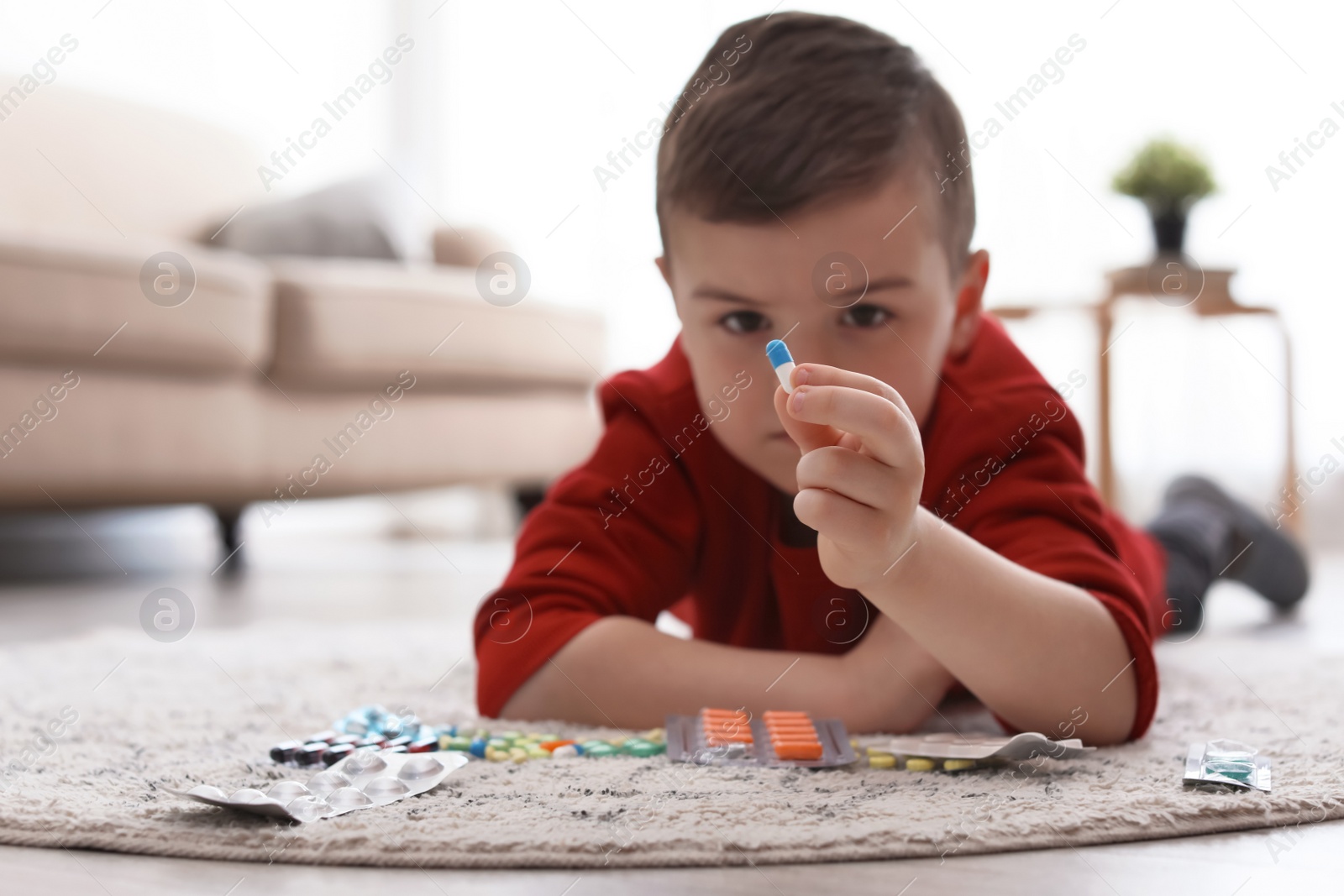 Photo of Little child with different pills on floor at home. Household danger