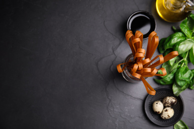 Photo of Uncooked buckwheat noodles and ingredients on grey table, flat lay. Space for text