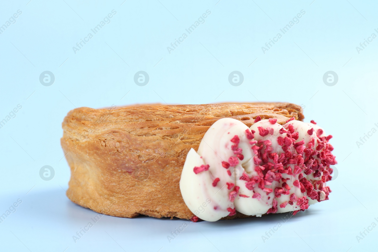 Photo of One supreme croissant with cream on light blue background, closeup. Tasty puff pastry