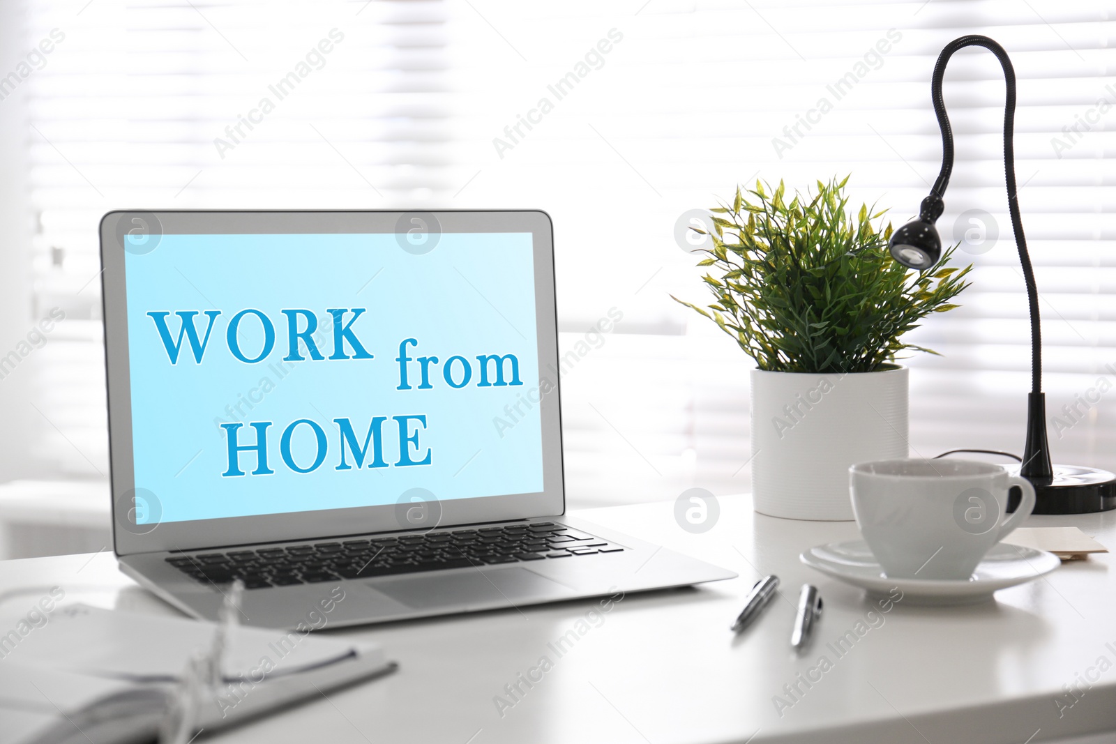 Image of Modern laptop with text WORK FROM HOME on office table