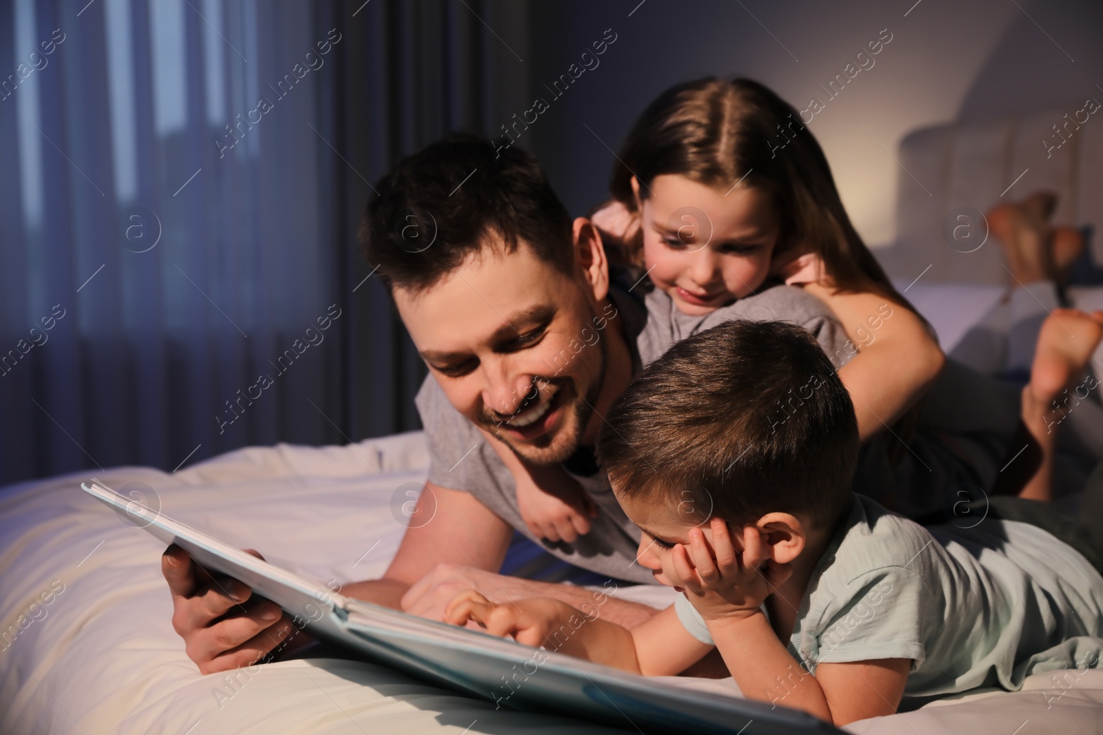 Photo of Father reading bedtime story to his children at home