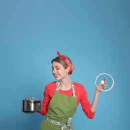 Photo of Young housewife with pot on light blue background
