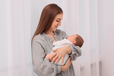 Mother with her cute newborn baby indoors