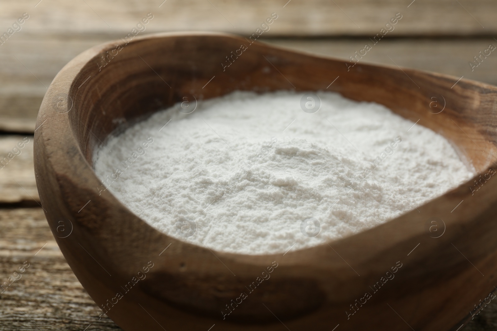 Photo of Baking powder in bowl on wooden table, closeup