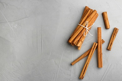 Aromatic cinnamon sticks on grey table, flat lay. Space for text