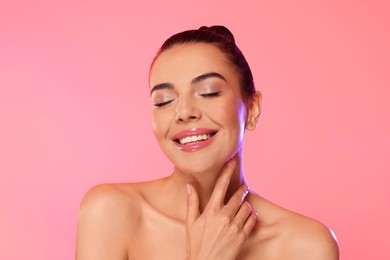 Photo of Portrait of young woman with beautiful makeup on light pink background