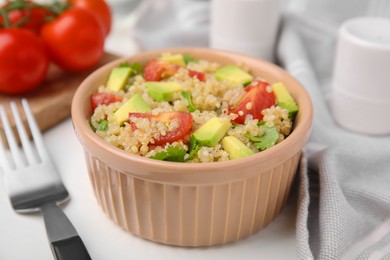 Delicious quinoa salad with tomatoes, avocado and parsley served on white table