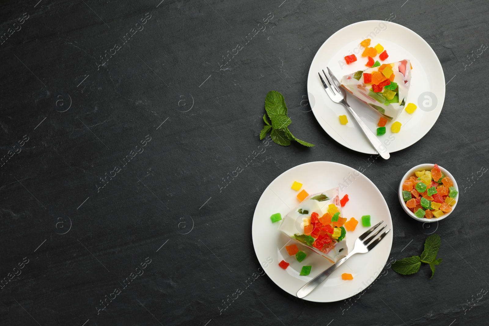 Photo of Delicious broken glass jelly dessert on black table, flat lay. Space for text