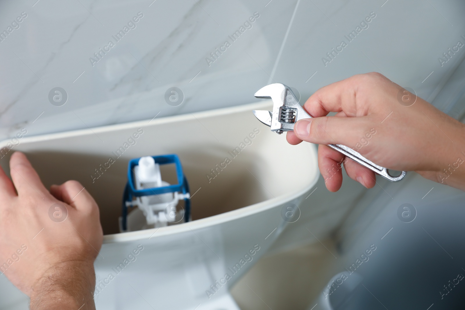 Photo of Professional plumber repairing toilet in bathroom, closeup