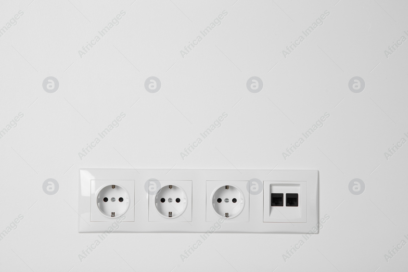 Photo of Many power sockets with ethernet plate on white wall indoors. Space for text