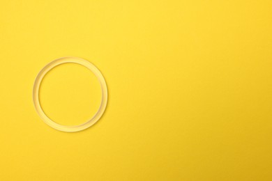 Photo of Diaphragm vaginal contraceptive ring on yellow background, top view. Space for text