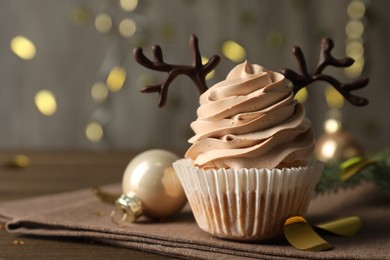 Photo of Tasty Christmas cupcake with chocolate reindeer antlers on wooden table, closeup. Space for text