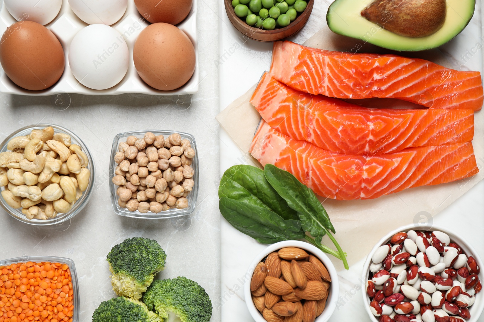 Photo of Products rich in protein on light marble table, flat lay