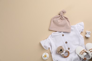 Photo of Flat lay composition with baby clothes and accessories beige background, space for text