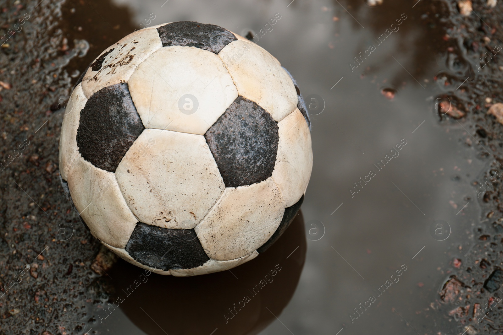 Photo of Dirty soccer ball in muddy puddle, closeup