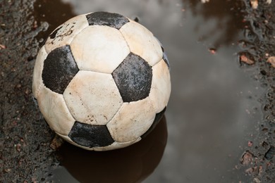 Dirty soccer ball in muddy puddle, closeup