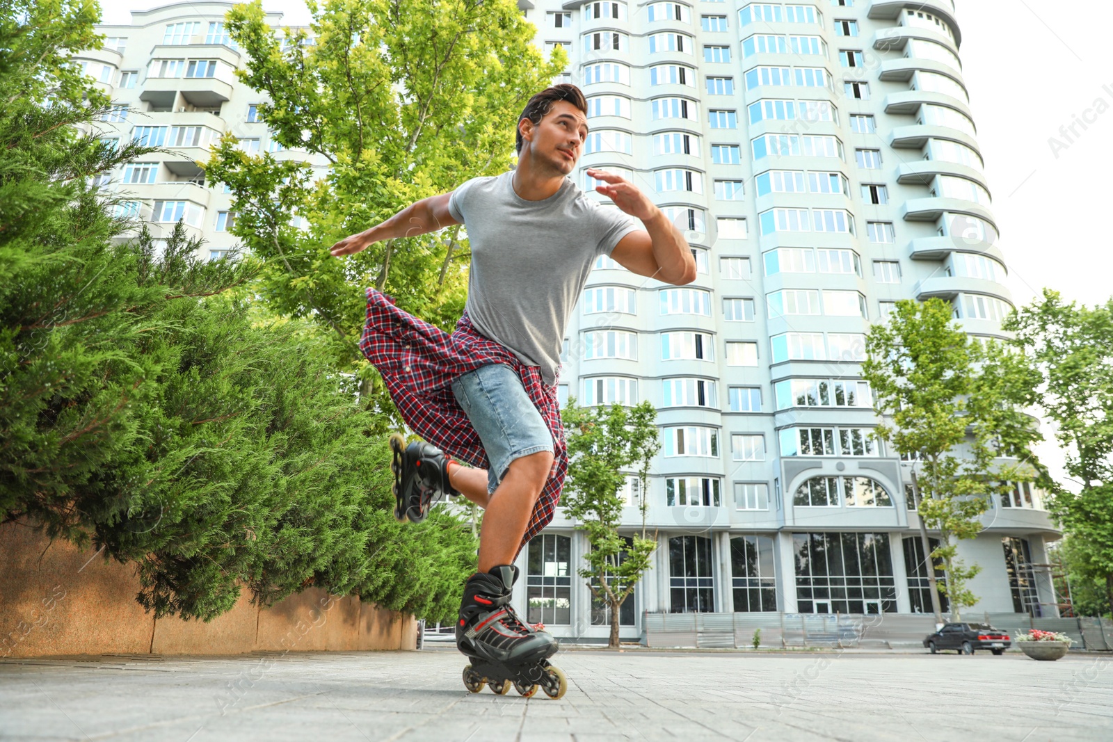 Photo of Handsome young man roller skating outdoors. Recreational activity